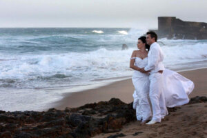 Bride and groom on the beach looking at stormy ocean