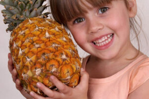 small girl holding a pineapple