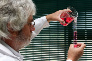 lab technician pouring red substance into glass test tube