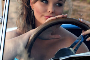 blue eyed brunette behind wheel of sportscar